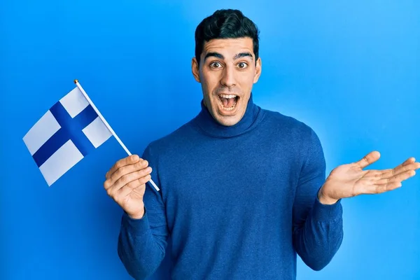 Hombre Hispano Guapo Sosteniendo Bandera Finlandia Celebrando Logro Con Sonrisa — Foto de Stock