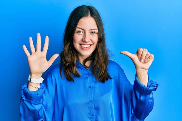 年轻的黑发女人穿着休闲的蓝色衬衫 带着自信和快乐的微笑 用手指指了指六号 — 图库照片