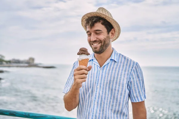 年轻的惊慌失措的男人在海滩上高兴地吃着冰激凌 — 图库照片