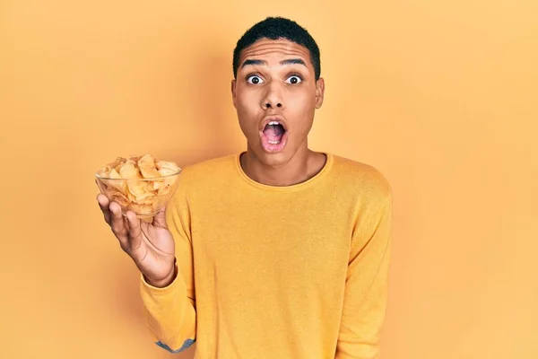 Young African American Guy Holding Potato Chip Scared Amazed Open — Stock Photo, Image