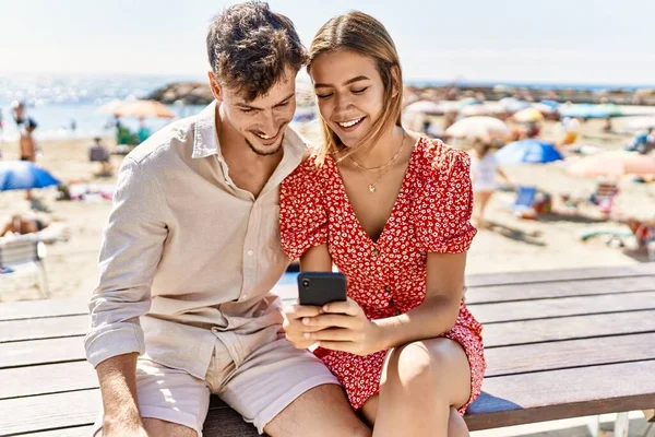 Young Hispanic Couple Vacation Using Smartphone Sitting Bench Beach — Stock Photo, Image