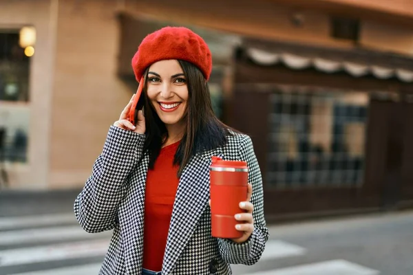 Genç İspanyol kadın akıllı telefondan konuşuyor ve şehirde kahve içiyor..