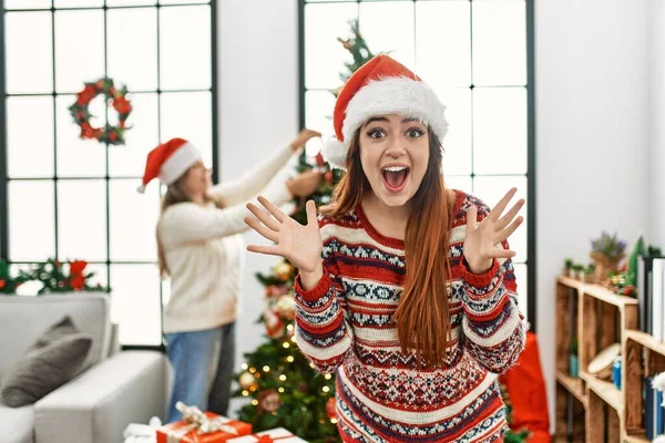 幸せな笑顔で勝利を祝うクリスマスツリーで家に立つ美しいカップルと手を上げて勝者の表情 — ストック写真