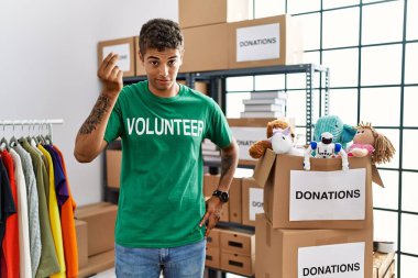 Bağışlarda gönüllü tişört giyen genç, yakışıklı İspanyol adam İtalyan jesti yapıyor. Elleri ve parmakları kendinden emin. 