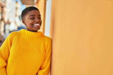 Genç Afrikalı Amerikalı kadın gülümseyerek şehirde mutlu mesut duruyor..