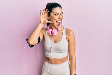 Spor kıyafetleri giyen, kulaklık takan, ağzı kulaklarında gülümseyen, dedikoduları ve dedikoduları dinleyen İspanyol bir kadın. Sağırlık kavramı. 