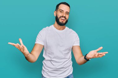 Sakallı, günlük beyaz tişörtlü, gülümseyen, yardım eli uzatan ve kabul gören genç bir adam.. 