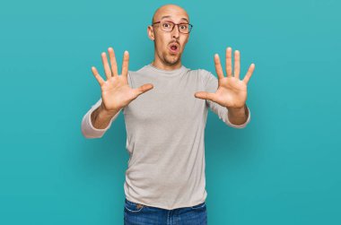 Sakallı, sıradan kıyafetler giyen, gözlüklü, korku ifadesinden korkan, el kol hareketi yapan, şok içinde bağıran kel bir adam. panik konsepti. 