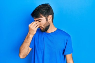 Günlük kıyafetler giyen genç İspanyol adam yorgun burnu ve gözleri ovuşturup yorgun ve baş ağrısı çekiyor. Stres ve hüsran kavramı. 