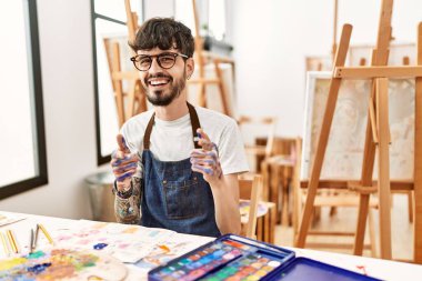 Resim stüdyosundaki sakallı İspanyol adam mutlu ve komik yüzüyle kamerayı işaret ediyor. iyi enerji ve titreşimler. 