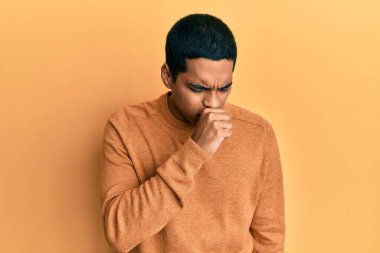 Kış süveteri giyen yakışıklı genç adam kendini iyi hissetmiyor ve soğuk algınlığı veya bronşitin belirtisi olarak öksürüyor. sağlık hizmeti kavramı. 