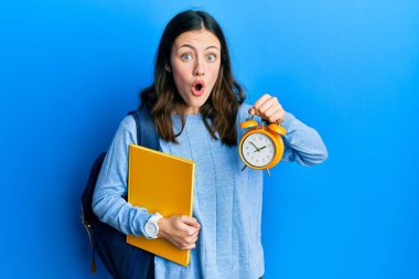 Çalar saati tutan genç esmer kadın şaşkınlık ve şaşkınlık ifadesi, korku ve heyecanlı yüz ifadesiyle dehşete düşmüş ve şok olmuştu.. 