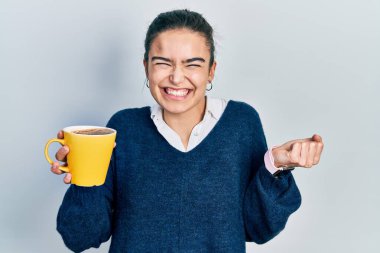 Kafkasyalı genç kız elinde kahveyle gururla bağırıyor zaferi ve başarıyı kutluyor. 