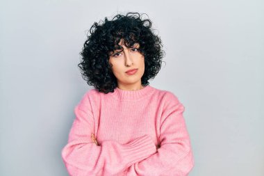 Orta Doğulu genç bir kadın gündelik kıyafetler giyiyor. Şüpheli ve gergin. Yüzünde çapraz kollu tasvip etmeyen bir ifade var. negatif kişi. 