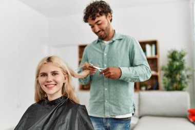 Genç adam evdeki kız arkadaşına saç kesiyor..