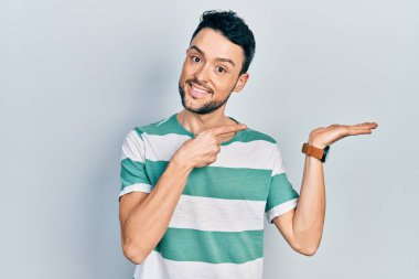 Gündelik kıyafetler giyen genç İspanyol adam kameraya hayret ediyor ve gülümsüyor.. 