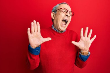 Gri saçlı, günlük kıyafetler giyen, gözlüklü, deli deli deli bağıran, sinirli ifadeli ve kolları havada yakışıklı bir adam. hüsran kavramı. 