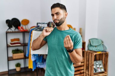 Satış mağazasında sakallı, alışveriş torbası tutan, el kol hareketi yapan, maaş ödemesi isteyen, milyonerlik işi yapan genç yakışıklı bir adam. 