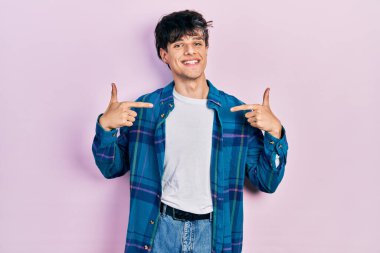 Yakışıklı hippi genç adam, günlük beyaz tişört ve klasik gömlek giyiyor. Kendine güvenen, gülümseyen, kendini gururlu ve mutlu gösteren.. 