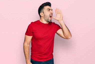 Kırmızı tişörtlü İspanyol sakallı bir adam el pençe divan durup bağırıyor. iletişim konsepti. 