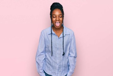 Genç Afro-Amerikan kadın, günlük kıyafetler giyip, dillerini komik bir ifadeyle dışarı çıkarıyor. duygu kavramı. 