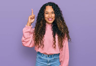 Kıvırcık saçlı, sıradan bir kazak giyen genç İspanyol kadın başarılı bir fikri işaret ediyor. Heyecanlı ve mutlu. Bir numara.. 