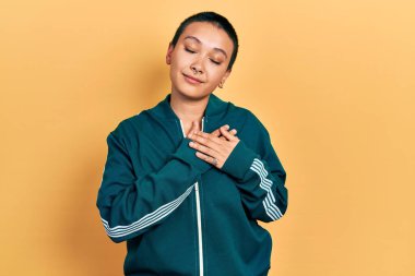 Kısa saçlı, spor ceketli, göğsünde elleri kapalı, yüzünde minnet ifadesi olan güzel İspanyol bir kadın. sağlık kavramı. 