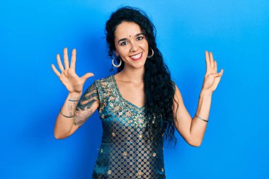 Bindi ve geleneksel kurta elbisesi giyen genç bir kadın dokuz numarayı gösterip işaret ederken kendinden emin ve mutlu gülümsüyor.. 