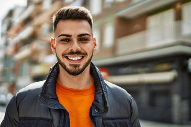 Yakışıklı, sakallı, neşeli ve kendine güvenen, kışlık palto giyen bir İspanyol.