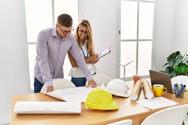 Mimarlık stüdyosunda çalışırken gülümseyen iki genç mimar..