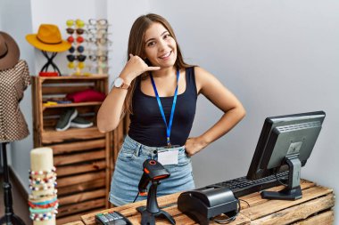 Genç esmer kadın perakende dükkanında açık mesajla pankart tutuyor gülümsüyor telefonla el ve parmaklarıyla telefonla konuşuyor gibi yapıyor. iletişim kavramları. 