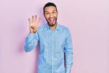 Sakallı, günlük mavi tişörtlü İspanyol adam dört numarayı gösterip işaret ederken kendinden emin ve mutlu bir şekilde gülümsüyor.. 