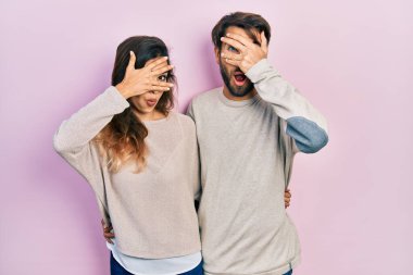 Gündelik giysiler giyen genç İspanyol çift şok içinde yüzlerini ve gözlerini kapayarak utangaç bir ifadeyle parmaklarının arasından bakıyor.. 