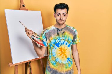 Genç İspanyol adam paletle resim çiziyor, resim sehpasında komik suratıyla yanaklarını şişiriyor. Havayla şişmiş ağız, çılgın bir ifade.. 