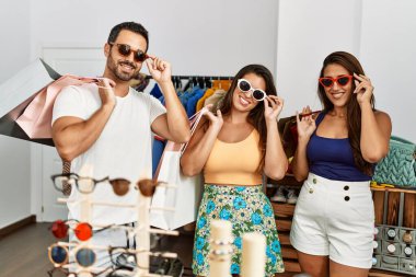 Bir grup İspanyol gülümseyen insan elbise mağazasında güneş gözlüğü denerken mutlu olurlar..