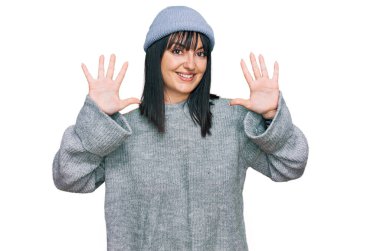 Şirin yün şapkalı genç İspanyol kadın on numarayı gösterip işaret ederken kendinden emin ve mutlu bir şekilde gülümsüyor.. 