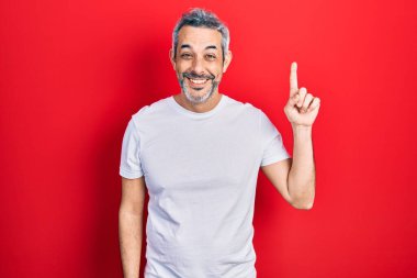 Gri saçlı, sıradan beyaz tişörtlü yakışıklı orta yaşlı bir adam başarılı bir fikri işaret ediyor. Heyecanlı ve mutlu. Bir numara.. 