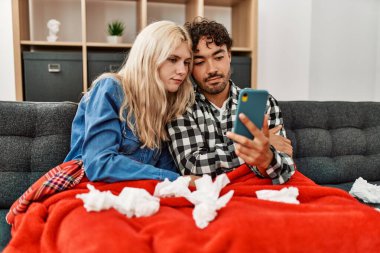 Evde akıllı telefon kullanan genç ve hasta bir çift..