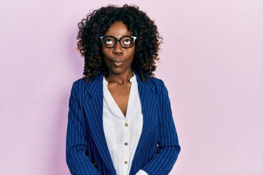 Genç Afro-Amerikalı kadın iş kıyafetleri ve gözlük takıyor dudaklarıyla balık suratı yapıyor, çılgınca ve komik jestler yapıyor. Komik ifade. 