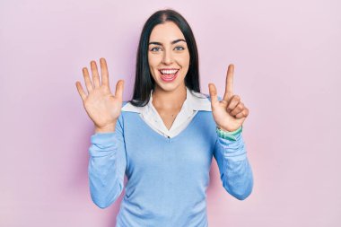 Pembe arka planda duran mavi gözlü güzel kadın yedinci parmaklarını gösterip işaret ederken kendinden emin ve mutlu gülümsüyor.. 