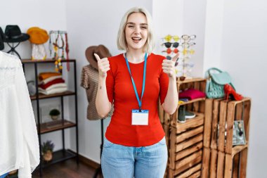 Perakende satış mağazasında müdür olarak çalışan beyaz bir kadın. Elleriyle olumlu jest yapıyor. Gülümsüyor ve mutlu. Neşeli ifade ve kazanan jest. 