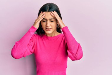 Genç İspanyol kadın stres yüzünden elleri başının üstünde gündelik giysiler giyiyor. migren ağrısı. 
