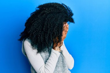 Afro saçlı, sıradan bir kazak giyen, suratını elleriyle örten ve ağlayan Afro-Amerikan bir kadın. depresyon kavramı. 