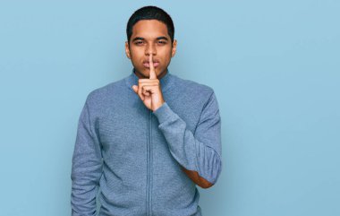 Gündelik kazak giyen genç, yakışıklı İspanyol adam parmakları dudaklarında sessiz olmak istiyor. sessizlik ve gizli konsept. 