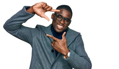 İş kıyafetleri ve gözlük takmış, gülümseyen, elleri ve parmakları mutlu yüzlü genç Afro-Amerikan bir adam. yaratıcılık ve fotoğrafçılık kavramı. 