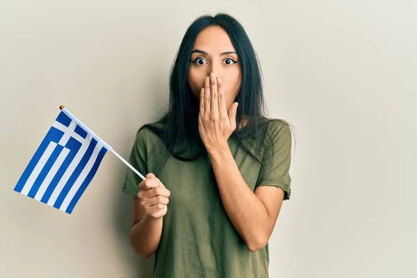 Young Hispanic Girl Holding Greece Flag Covering Mouth Hand Shocked — Stock Photo, Image