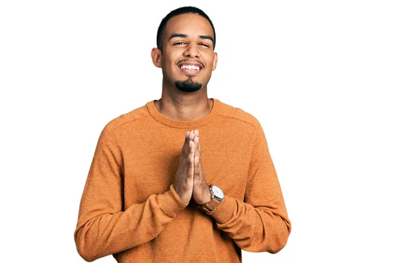 若いアフリカ系アメリカ人男性が手を携えて祈っているカジュアルな服を着て一緒に自信を笑顔許しを求めて — ストック写真