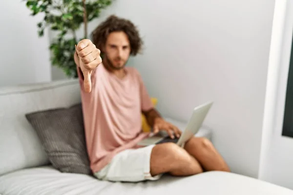Jovem Hispânico Sentado Sofá Casa Usando Laptop Olhando Infeliz Irritado — Fotografia de Stock