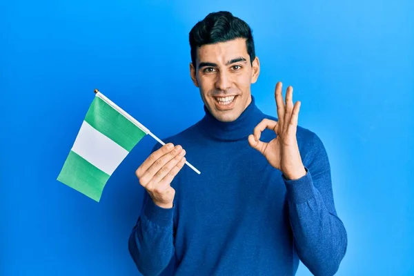 Snygg Latinamerikansk Man Håller Nigeria Flagga Gör Tecken Med Fingrar — Stockfoto