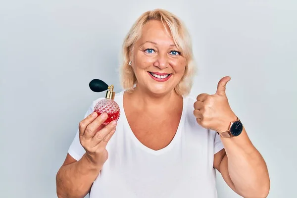 Medelålders Blond Kvinna Som Håller Parfym Leende Glad Och Positiv — Stockfoto